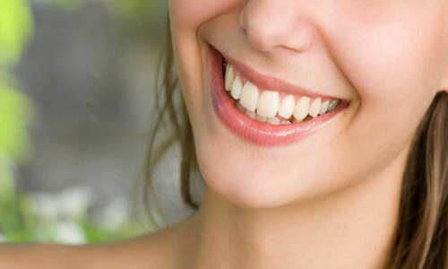 Close-up picture of a smiling woman with long brown hair and with perfect teeth, showing her happiness with the dental crowns she received at Premier Holistic Dental in beautiful Costa Rica.