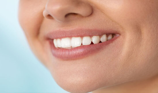 Close-up portrait picture of a smiling woman with perfect white teeth, smiling at the camera, and illustrating her happiness with the bone grafts procedure she had at Premier Holistic Dental in beautiful Costa Rica.