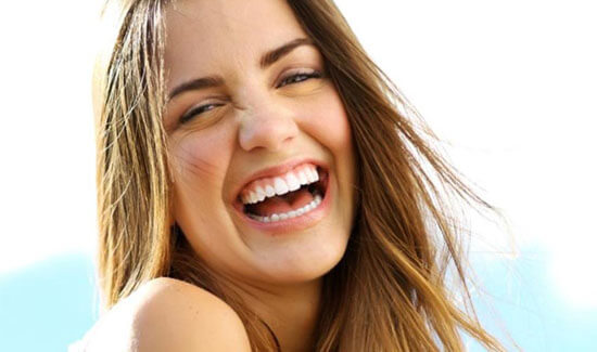 Close-up portrait picture of a smiling woman with long sandy brown hair and with perfect teeth, looking directly at the camera and showing her happiness with the cavitation procedure she had at Premier Holistic Dental in beautiful Costa Rica.