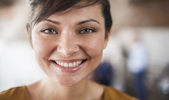 Portrait picture of a smiling woman with short brown hair and brown eyes, looking directly at the camera and showing her happiness with the dental bonding she had at Premier Holistic Dental in beautiful Costa Rica.