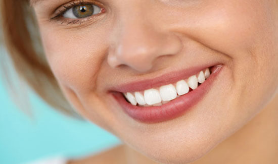 Close-up portrait picture of a smiling woman with short brown hair and with perfect teeth, facing the camera and showing her happiness with the homeopathy procedure she had at Premier Holistic Dental in beautiful Costa Rica.