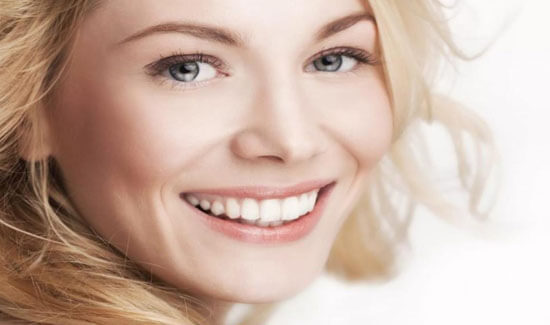 Close-up portrait picture of a smiling woman with long blonde hair and with perfect teeth, looking directly into the camera and showing her happiness with the laser treatments she had at Premier Holistic Dental in beautiful Costa Rica.
