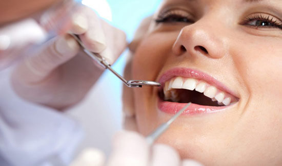 Picture of a woman with perfect teeth sitting in a dental chair, smiling at the camera, illustrating her happiness with the oral surgery procedure she had at Premier Holistic Dental in beautiful Costa Rica.