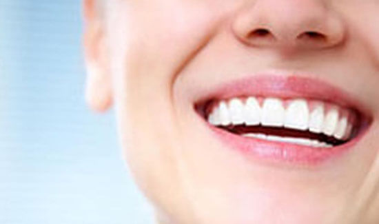 Close-up portrait picture of a smiling woman with perfect teeth, facing the camera and illustrating her happiness with the ozone therapy procedure she had at Premier Holistic Dental in beautiful Costa Rica.
