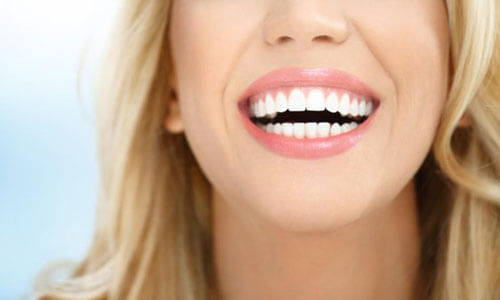 Close-up picture of a smiling young woman with long blonde hair and perfect teeth, happy with her Holistic Huggins-Grube Protocol treatment at Premier Holistic Dental in beautiful Costa Rica.