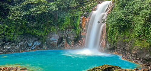 Picture of a beautiful natural waterfall in Costa Rica you may visit while having dental work at Premier Holistic Dental in Costa Rica.  Also in the picture is a blue lake created by the waterfall.